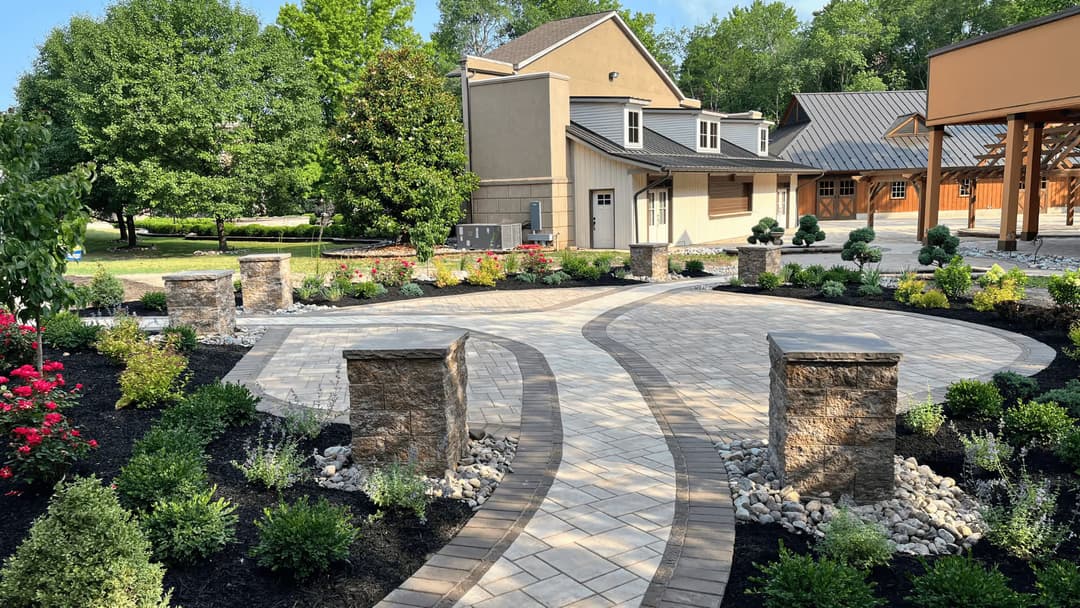 Modern outdoor patio with curved stone pathways, lush gardens, and a stylish house backdrop.