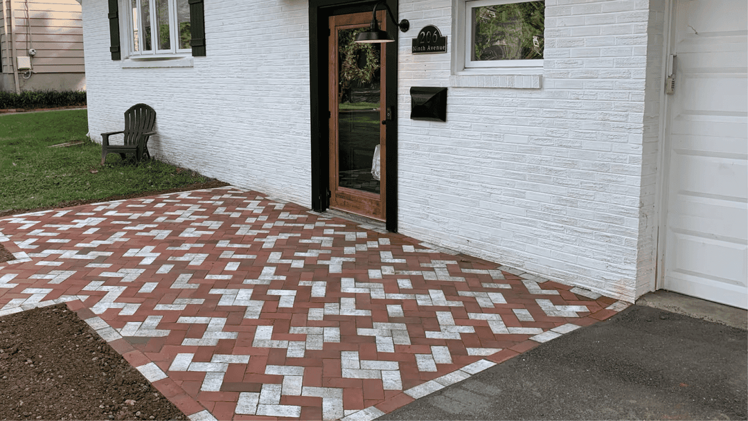 Exterior view of a home with a decorative red and white brick pathway leading to the entrance.