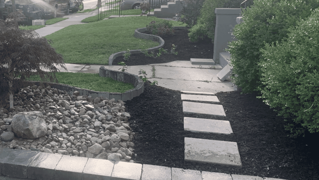 Landscaped garden path with stone steps, mulch, and decorative rock features.