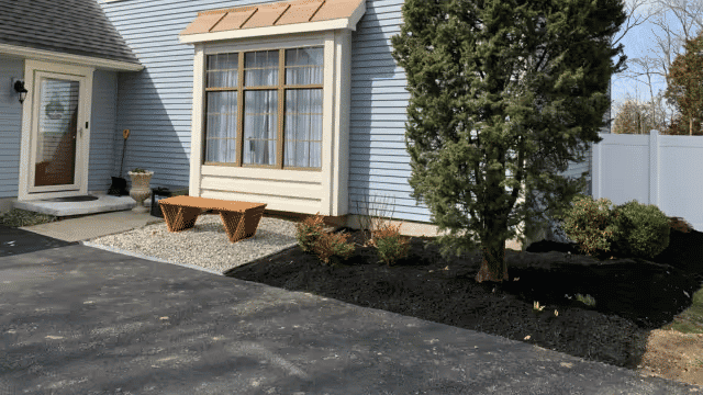 Modern home exterior with landscaped garden, decorative bench, and gravel detail.
