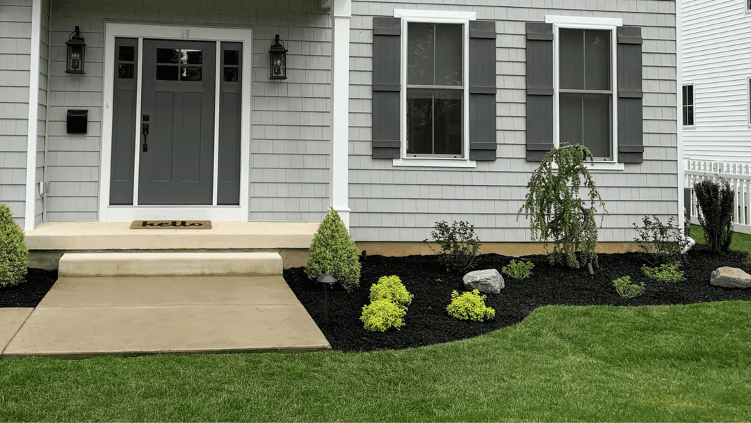 Modern gray house with a welcoming entrance, manicured lawn, and decorative landscaping.
