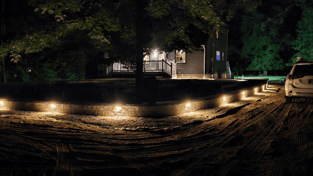 Outdoor landscape lighting illuminating a home at night with a gravel pathway.