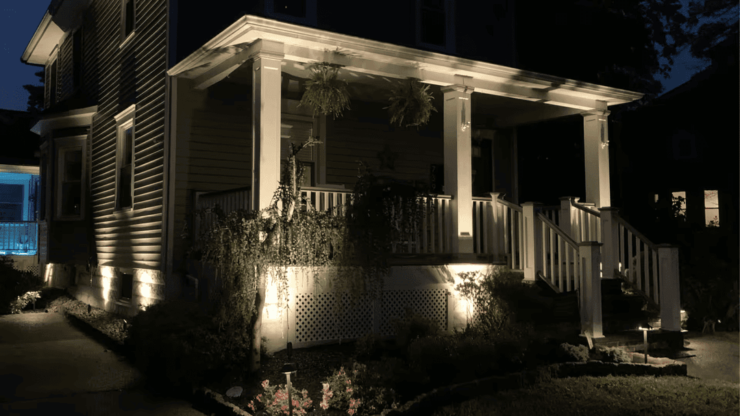 Illuminated porch and landscaping at night showcasing modern home exterior design.