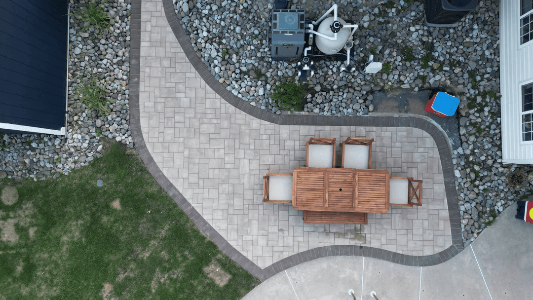 Aerial view of a patio with a wooden dining set surrounded by stone landscaping.
