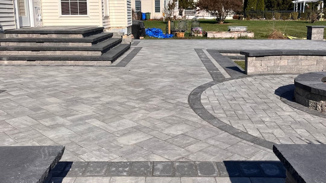 Beautifully paved outdoor patio with steps, landscaping, and stone seating area.