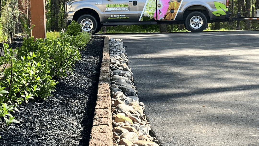 Beerman Landscaping truck parked beside a landscaped yard with stone edging and mulch.
