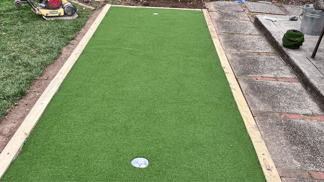 Artificial turf installation for a backyard putting green with two holes.