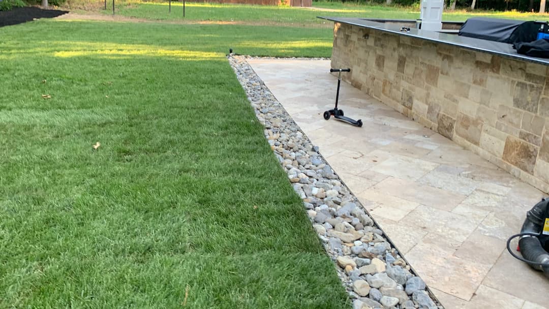 Lush green lawn with stone border and patio area, ideal for outdoor living space.