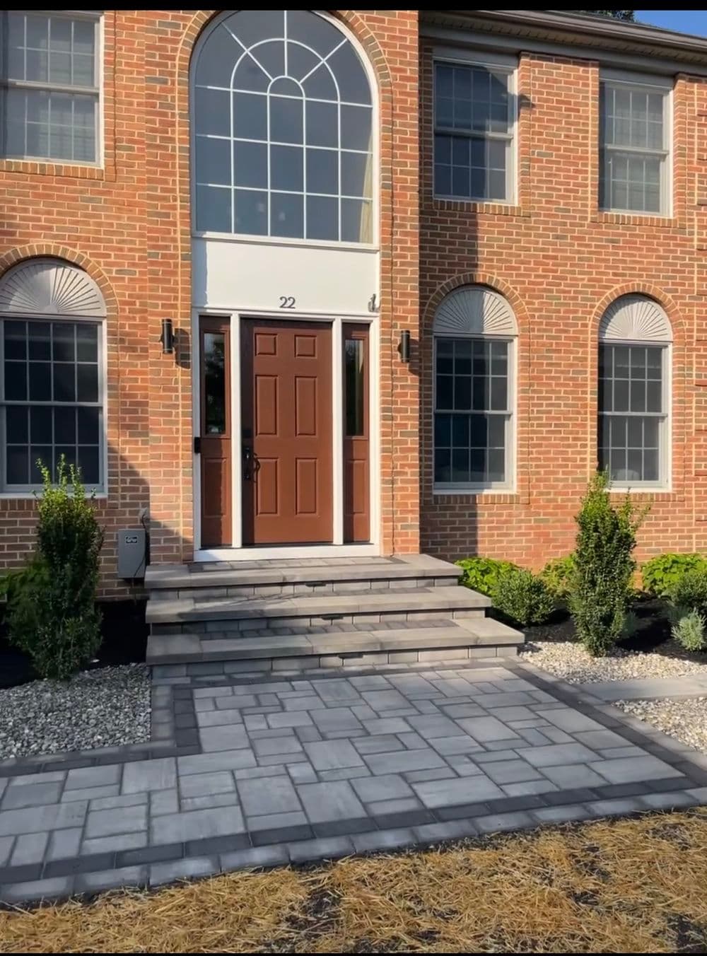 Brick home exterior with arched windows, brown door, and stone pathway at 22 Main Street.