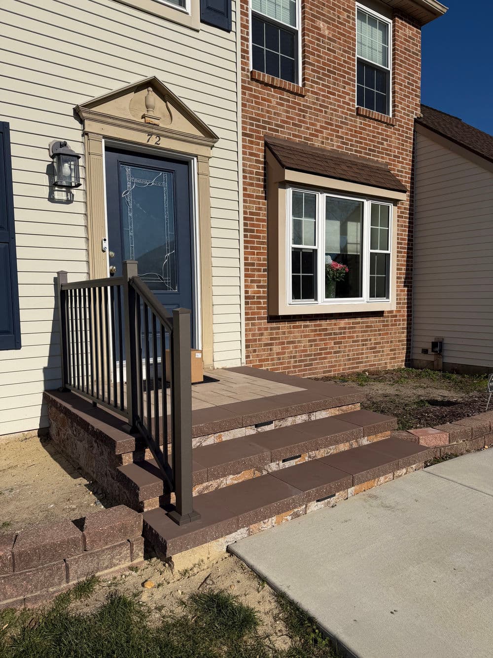 Front porch with steps and railing at brick and siding home, number 72. Welcoming exterior view.