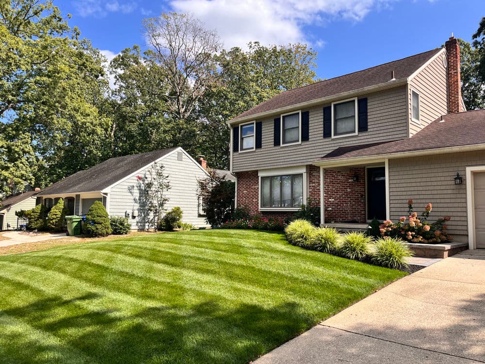 Two charming suburban homes with manicured lawns and clear blue skies. Ideal neighborhood setting.