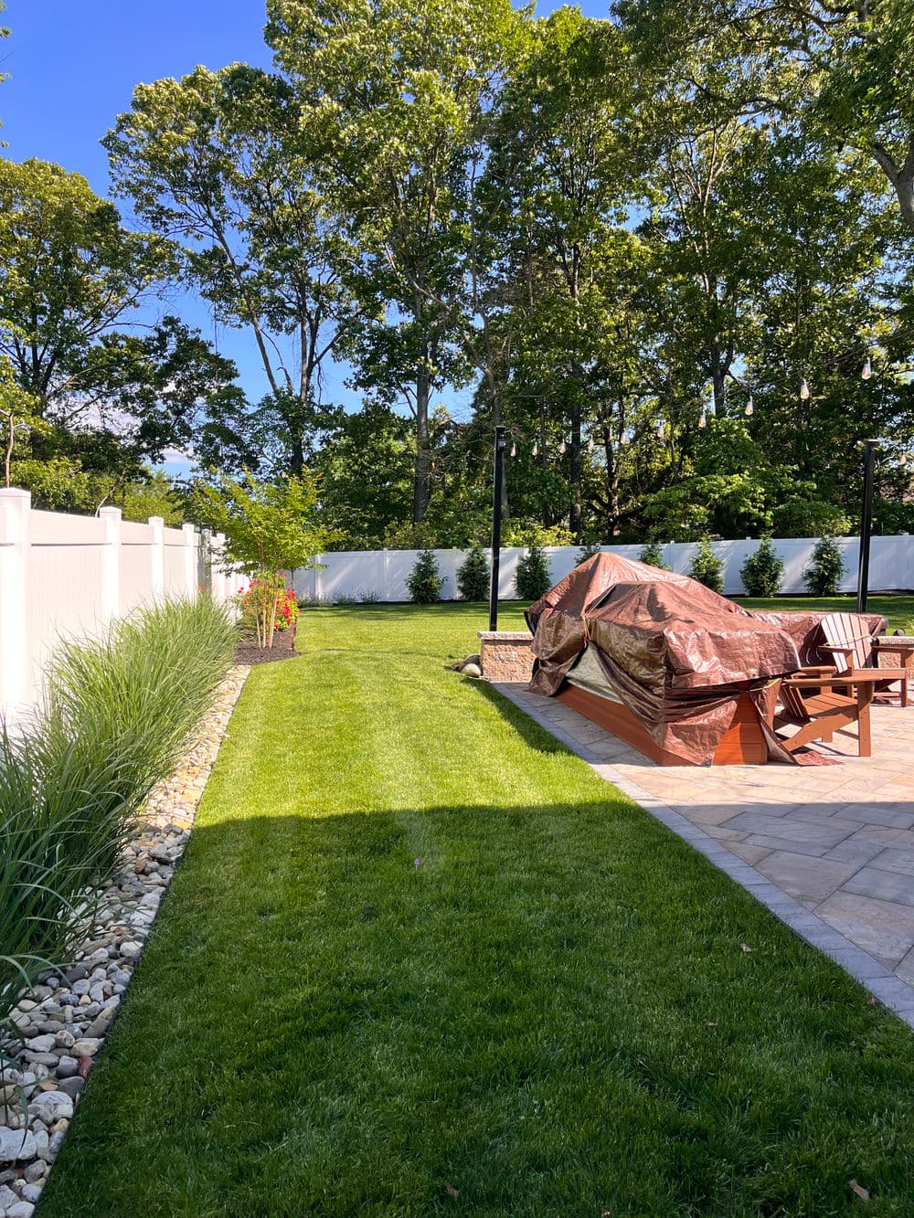 Lush green backyard with patio, covered hot tub, and landscaped garden.