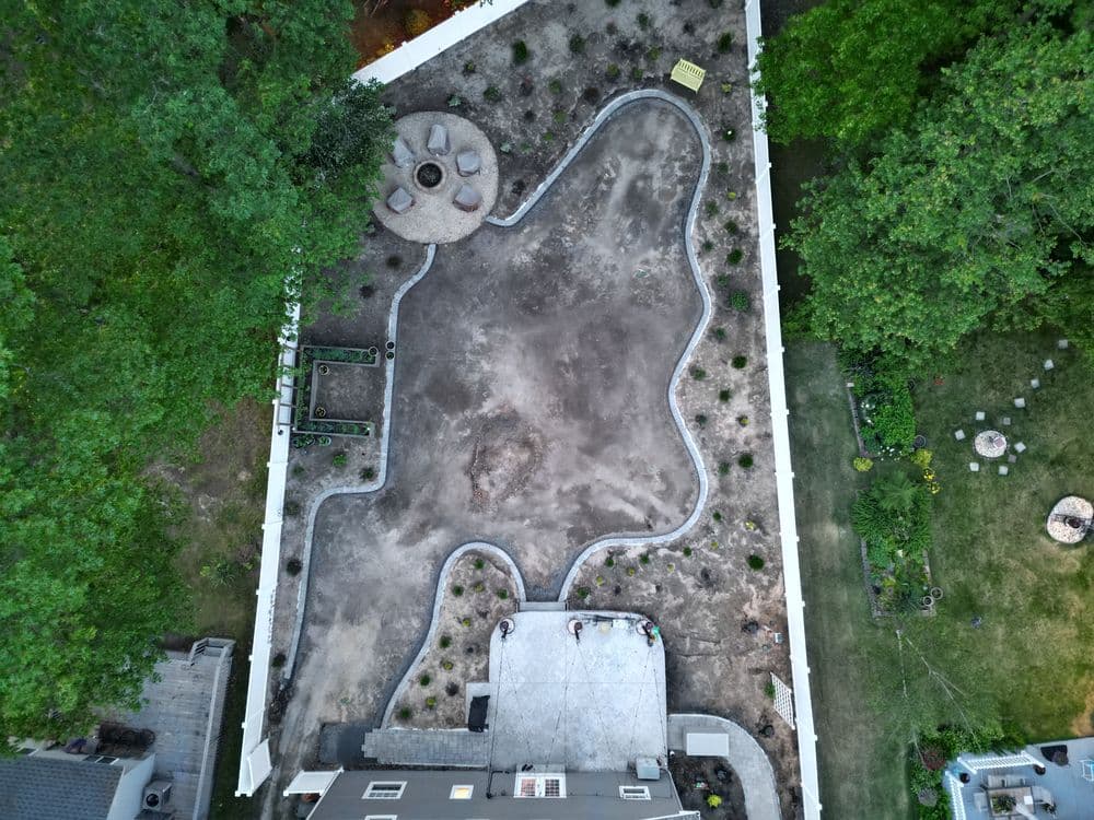Aerial view of a landscaped backyard with a circular patio and planting areas.