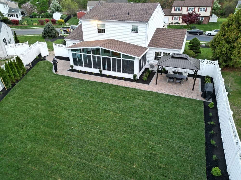 Aerial view of a landscaped backyard featuring a patio, gazebo, and freshly laid sod.